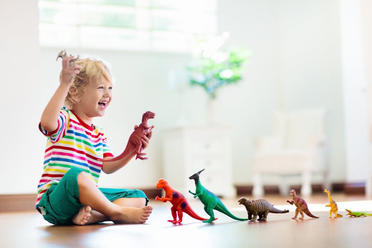 Child playing with toy dinosaurs. Kids toys.